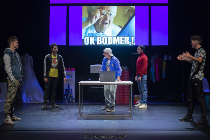 lauréat label 2021
in solidum
les 5 comédiens sont debout sur le plateau avec un écran qui projette une image d'une personne âge qui dit " ok boomer"
